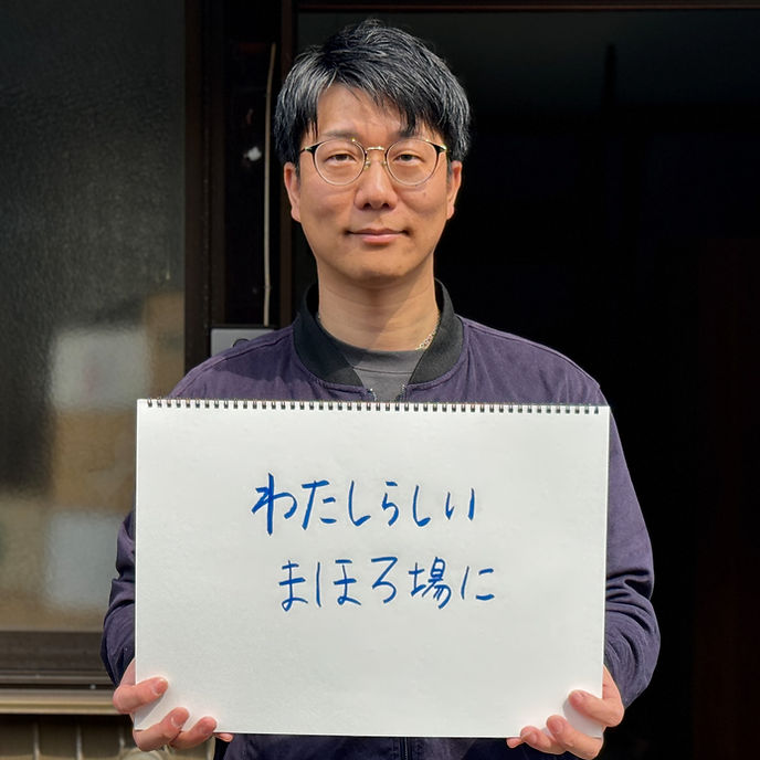 星野 卓也さんが手書きのメッセージボードを持つ写真