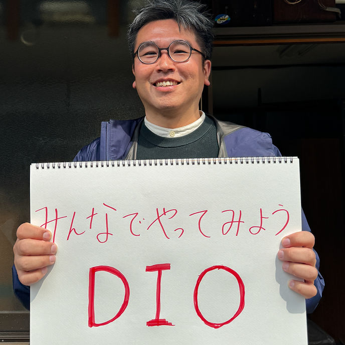 今西 浩二さんが手書きのメッセージボードを持つ写真