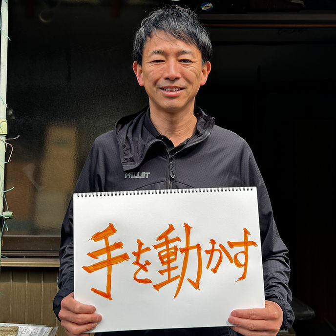 佐野 航さんが手書きのメッセージボードを持つ写真