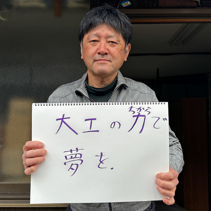 竹内 広幸さんが手書きのメッセージボードを持つ写真