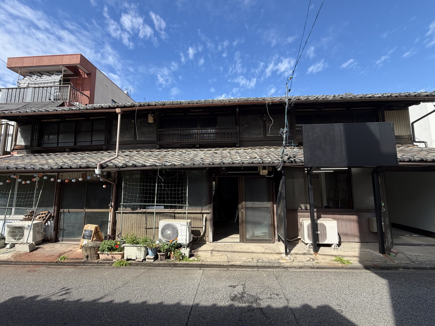 青空の下に建つ百人町の長屋正面